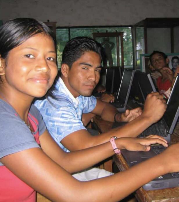 2 teens from nicaragua smiling over their computer keyboards
